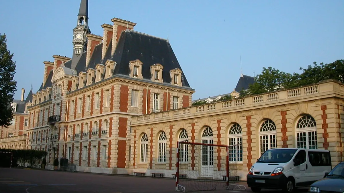 Le bâtiment principal du lycée Pasteur à Neuilly : façade de brique rouge et de pierre claire, toit d'ardoise, campanile surmonté d'une flèche, et une aile basse à arcades sur la cour.