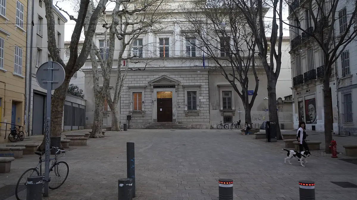 La place du Lycée à Marseille, pavée et plantée de platanes nus, avec la façade en pierre blanche du lycée Thiers et son fronton gravé au fond.