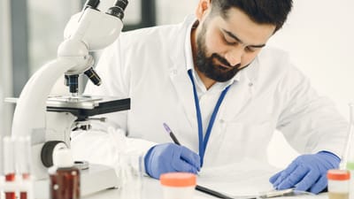 Scientifique masculin dans un laboratoire, examinant des échantillons et prenant des notes.