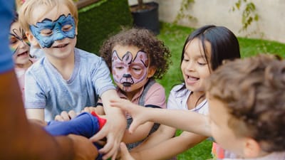 Groupe d'enfants avec des peintures sur le visage profitant du temps de jeu en plein air, riant et jouant à des jeux.