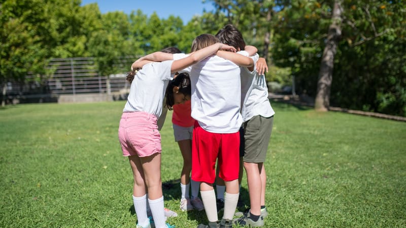 Groupe d'enfants rassemblés à l'extérieur s'engageant dans des activités de cohésion d'équipe.