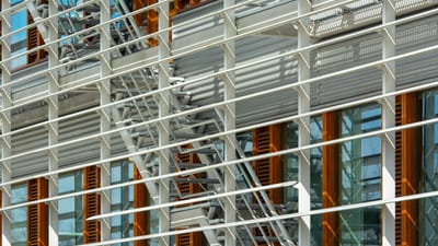 Vue détaillée d'une façade de bâtiment mettant en avant des structures métalliques et des fenêtres en verre, soulignant l'architecture urbaine.