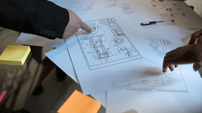 Des ingénieurs discutent de plans en blueprint dans un espace de travail, se concentrant sur le travail d'équipe et le design architectural.