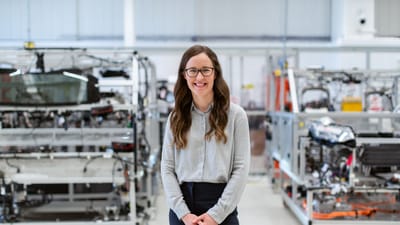 Femme ingénieure souriante se tenant avec confiance dans un cadre d'atelier industriel moderne.