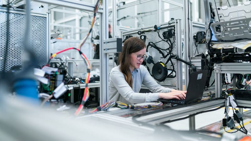 Une ingénieure se concentre sur son ordinateur portable au milieu d'équipements technologiques avancés dans un laboratoire.