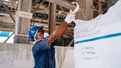 Un ouvrier industriel vérifie un grand sac de carbonate de sodium dans une usine de fabrication.