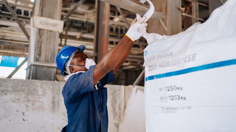 Un ouvrier industriel vérifie un grand sac de carbonate de sodium dans une usine de fabrication.