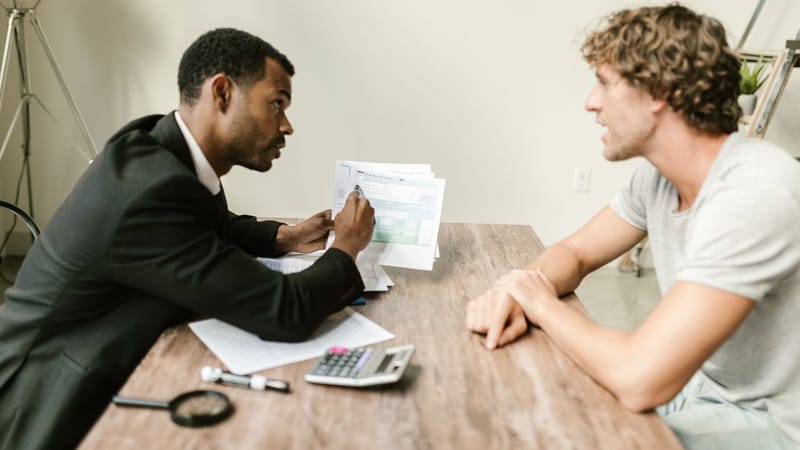 Un conseiller financier discute de documents avec un client à un bureau dans un bureau moderne.