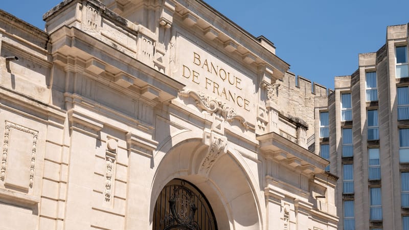 Élégante façade architecturale de la Banque de France à Avignon se détachant sur un ciel bleu azur.