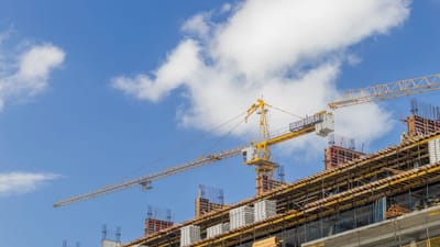 Un chantier de construction moderne avec des grues se détachant sur un ciel bleu azur, illustrant le développement urbain.