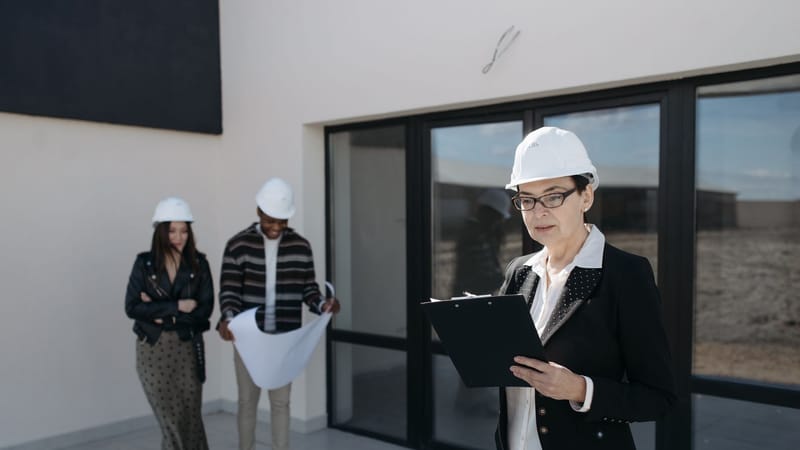 Architectes en casques de sécurité examinant des plans de construction sur un chantier.
