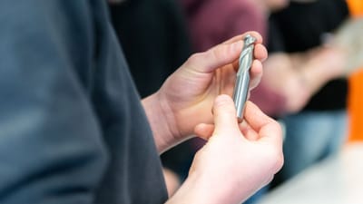 Des mains examinant soigneusement une mèche en métal lors d'une session d'atelier.