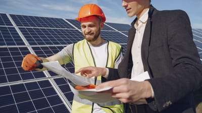 Deux ingénieurs examinent des plans pour l'installation de panneaux solaires, représentant le travail d'équipe dans les énergies renouvelables.