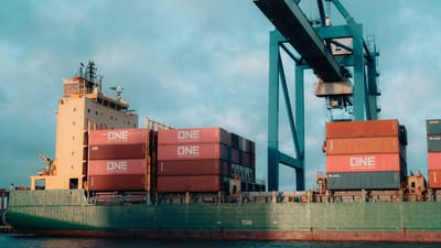 Grand cargo chargé de conteneurs colorés dans un port industriel animé.