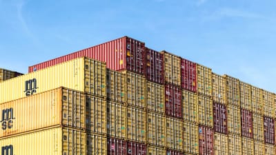 Conteneurs de fret colorés empilés dans le port de Hambourg sous un ciel bleu clair.