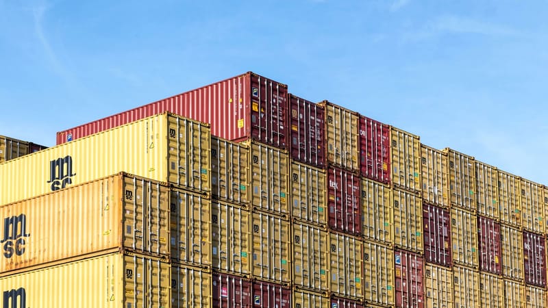 Conteneurs de fret colorés empilés dans le port de Hambourg sous un ciel bleu clair.
