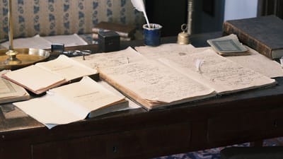 Bureau cosy avec un bureau vintage, des livres ouverts et une plume pour une atmosphère littéraire classique.