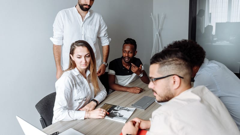Un groupe de collègues divers engagés dans une réunion d'affaires autour d'une table de bureau partagée.