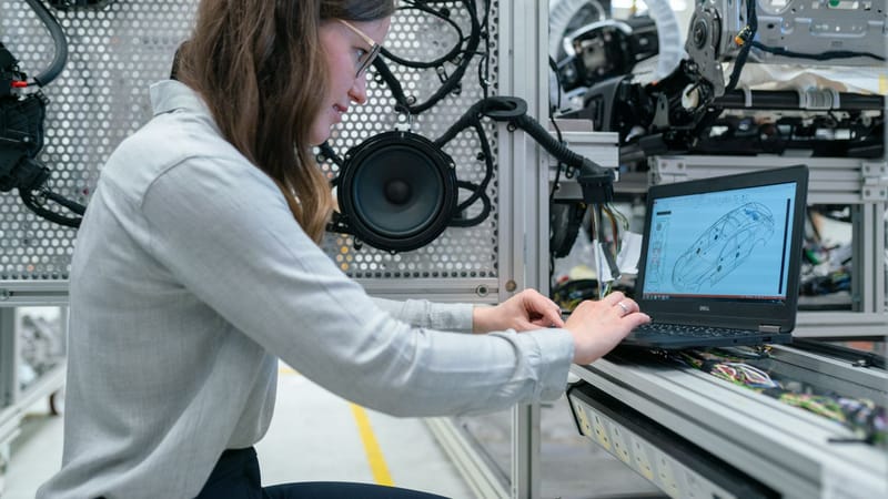Femme effectuant des recherches en ingénierie dans un atelier de systèmes audio en utilisant un ordinateur portable.