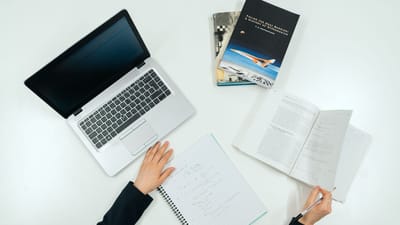 Vue de dessus d'un bureau de travail avec un ordinateur portable, des livres et des notes illustrant la productivité.