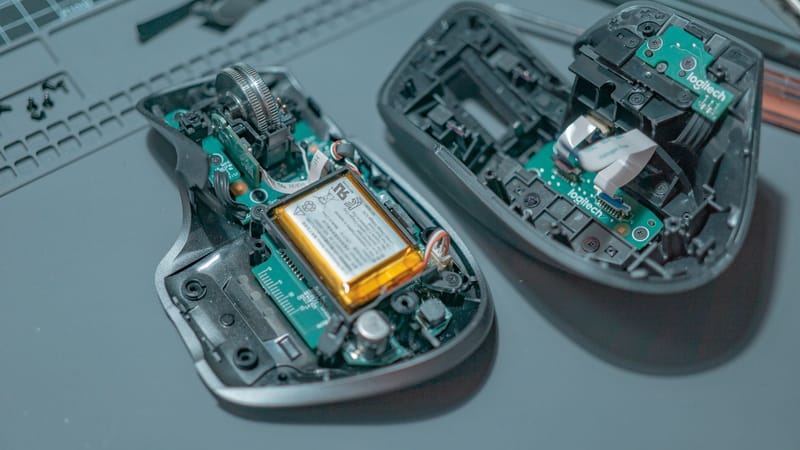 Gros plan d'une souris d'ordinateur démontée révélant des cartes de circuits internes et des composants.