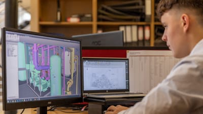 Ingénieur travaillant avec un logiciel CAO sur des écrans doubles dans un environnement de bureau.