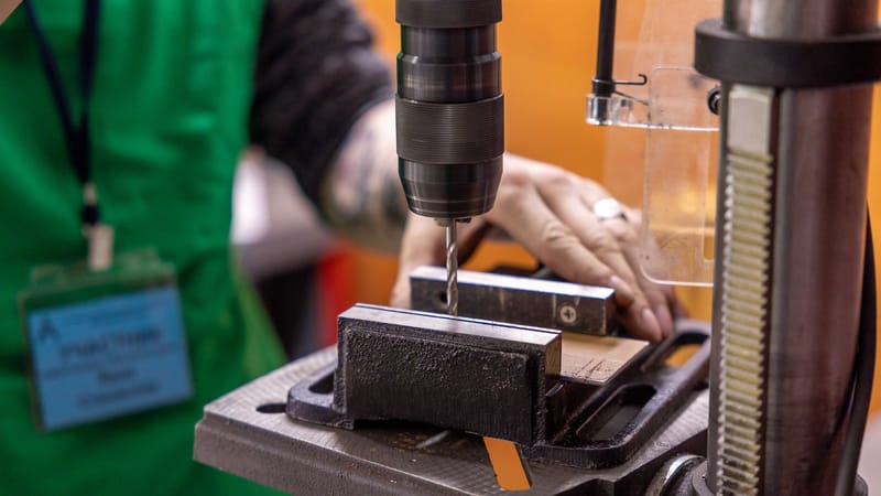 Vue détaillée d'une main utilisant une perceuse à colonne dans un atelier.