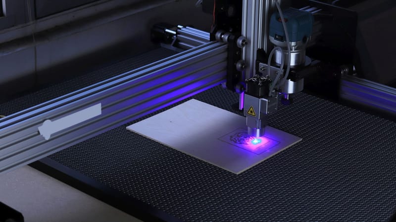 Gros plan d'une machine de gravure laser CNC traitant une pièce en bois.