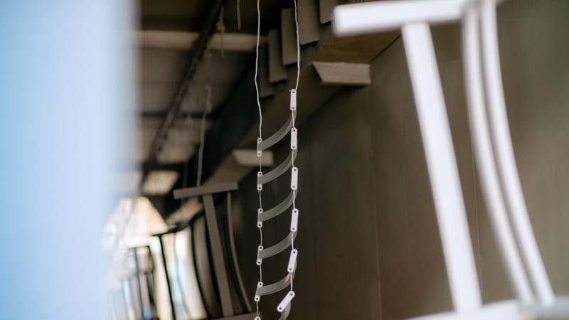 Gros plan de pièces métalliques industrielles suspendues dans un processus de revêtement, mettant en valeur les détails de fabrication.