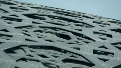 Vue en contre-plongée d'une façade en acier géométrique et complexe avec un design architectural contemporain.