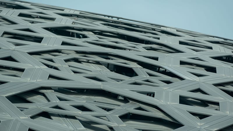 Vue en contre-plongée d'une façade en acier géométrique et complexe avec un design architectural contemporain.