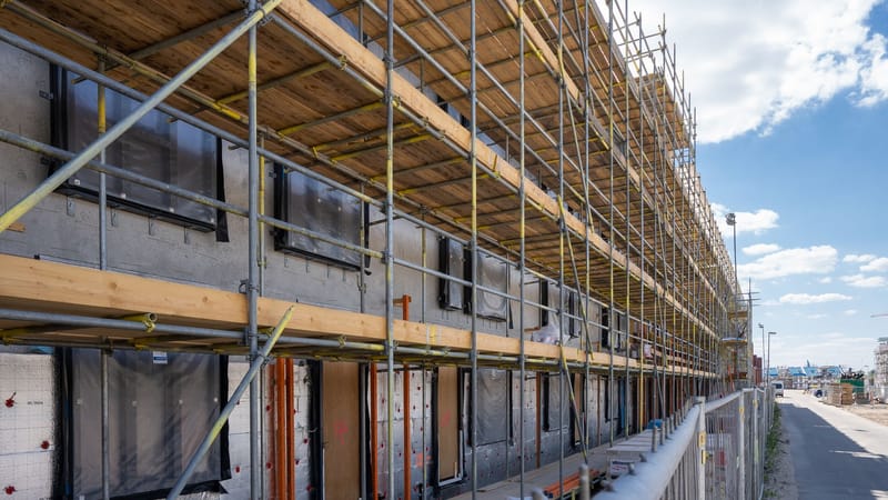 Échafaudages sur un site de construction en ville sous un ciel bleu dégagé.