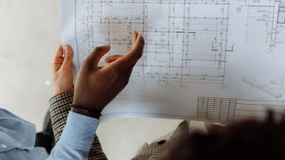 Vue approfondie de mains examinant un plan architectural détaillé avec des mesures précises.