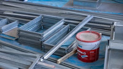Des piles de cadres en métal et un seau de peinture à l'intérieur d'un site de construction mettant en avant les matériaux de construction.