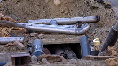 Gros plan de l'installation de canalisations urbaines sur un chantier de construction, montrant divers tuyaux et matériaux.