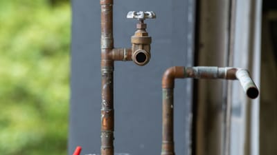 Vue détaillée d'une vieille conduite d'eau industrielle rouillée avec vanne, évoquant une esthétique industrielle vintage.