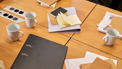 Un bureau de travail bien rangé avec des classeurs, des papiers et des tasses à café disposés de manière ordonnée, offrant une ambiance professionnelle.