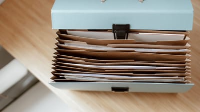 Une vue de dessus d'un dossier accordéon bleu rempli de documents de bureau organisés sur un bureau en bois.