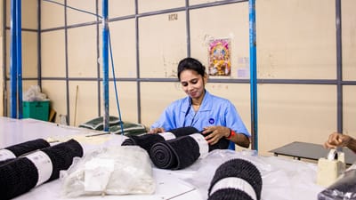 Femme travaillant à organiser des textiles dans un environnement d'usine, mettant en avant le travail manuel.
