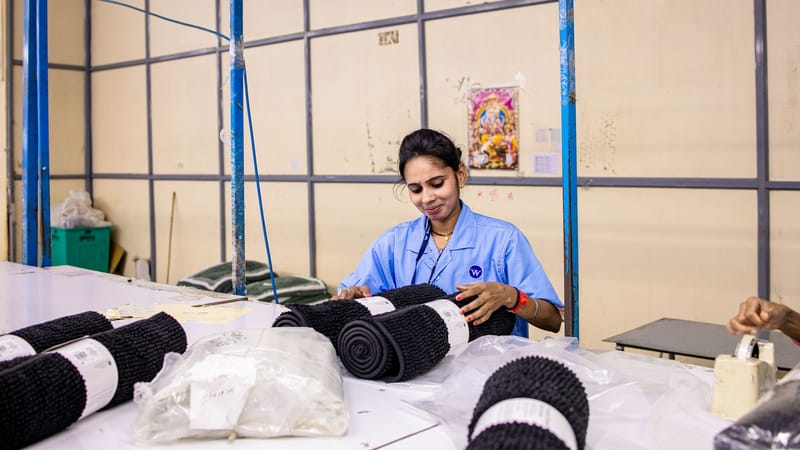 Femme travaillant à organiser des textiles dans un environnement d'usine, mettant en avant le travail manuel.