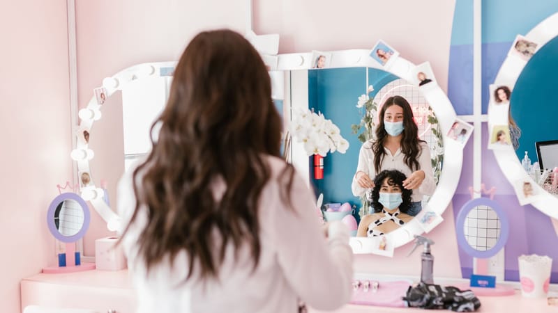 Coiffeur et client portant des masques dans un salon moderne, reflétant les mesures de sécurité pandémiques.