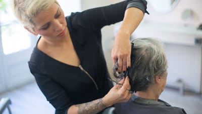 Un coiffeur avec un tatouage coupant les cheveux d'un client dans un salon.