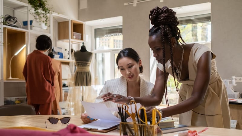 Des professionnels de la mode collaborant dans un studio de design moderne, révisant des créations.