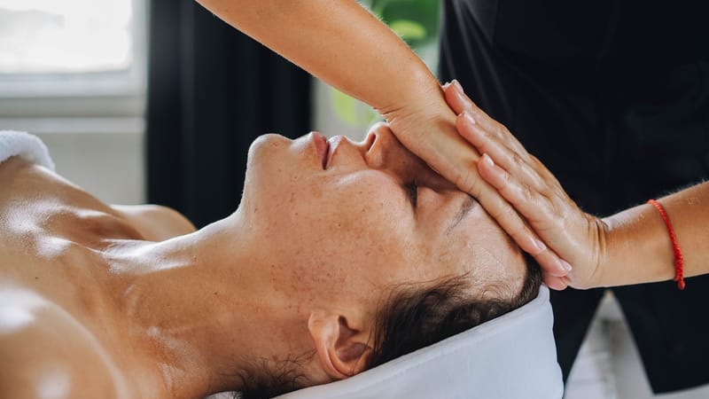 Femme recevant un massage facial apaisant dans un environnement de spa paisible.