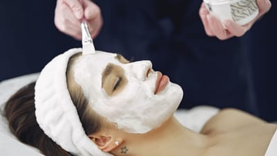 Gros plan sur une femme les yeux fermés profitant d'une application de masque facial apaisant dans un spa.