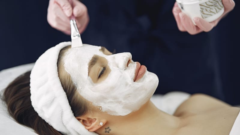 Gros plan sur une femme les yeux fermés profitant d'une application de masque facial apaisant dans un spa.