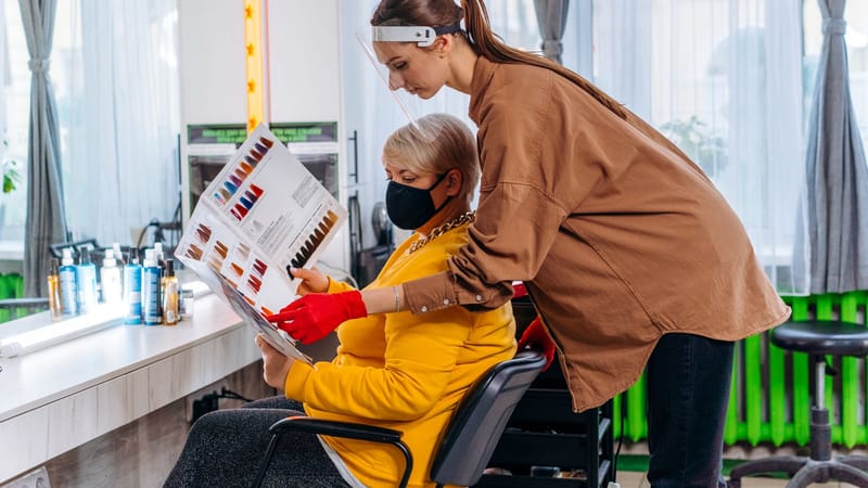 Coiffeur aidant un client à choisir la couleur de cheveux dans un salon moderne.