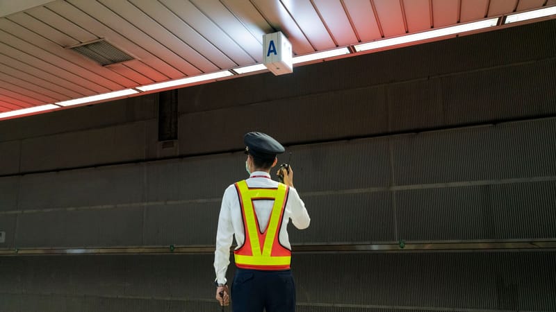 Un agent de sécurité communique par radio dans une gare de train vide.