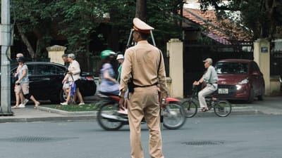 Un agent de la circulation gère une rue très fréquentée à Hanoi, au Vietnam, avec des piétons et des cyclistes.