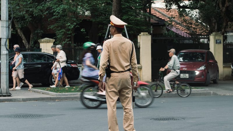 Un agent de la circulation gère une rue très fréquentée à Hanoi, au Vietnam, avec des piétons et des cyclistes.